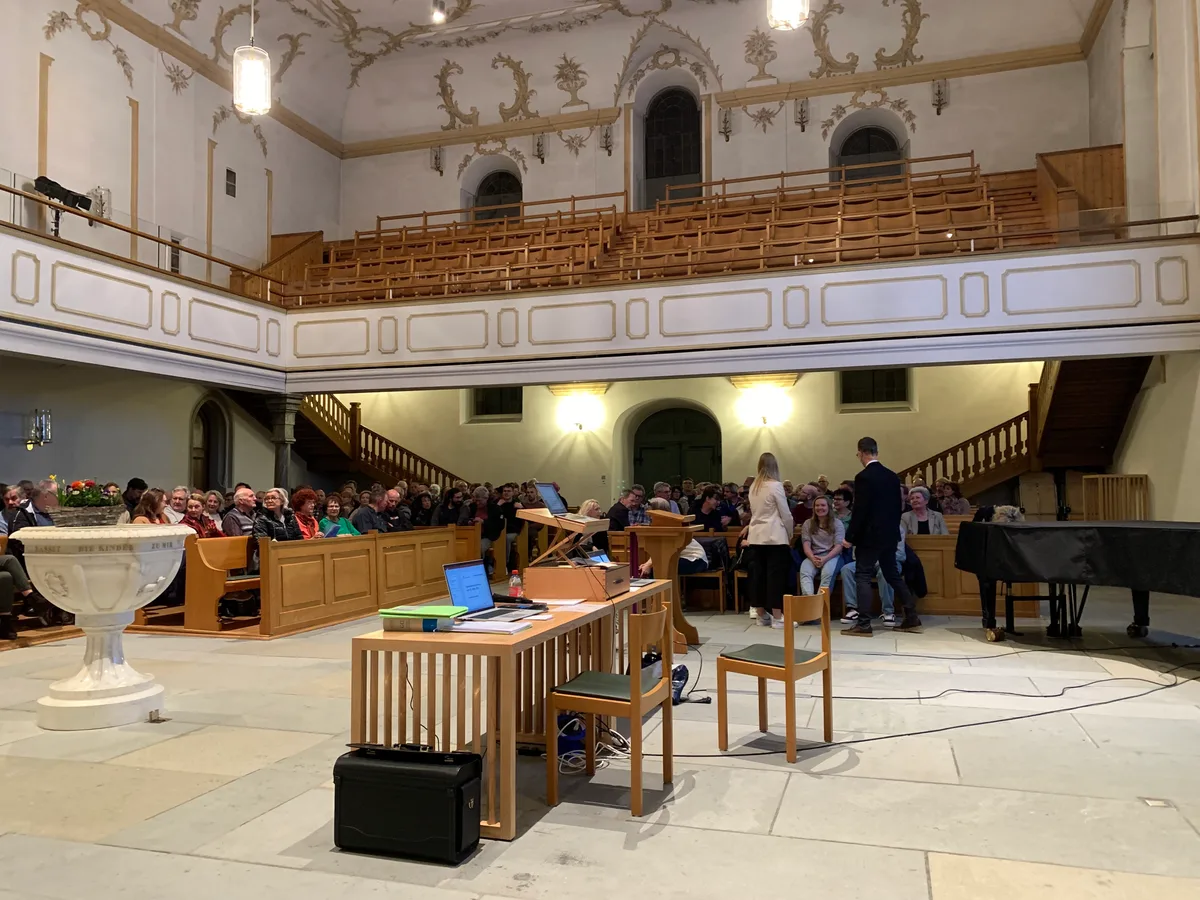 Leute sitzen in Kirchenbänken.